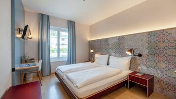 A bedroom with a bed, bedside tables, a desk, and a chair.