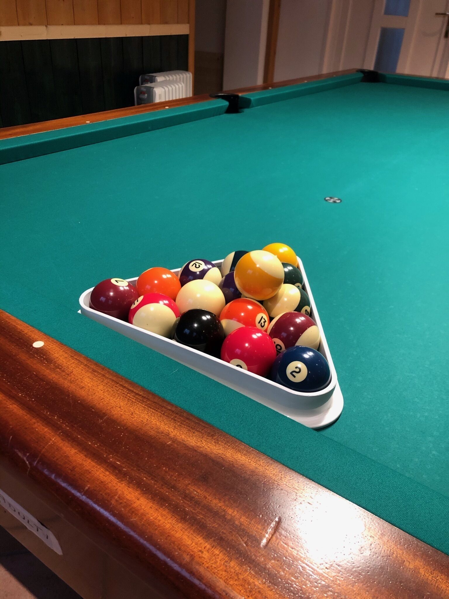 A pool table with a triangular rack filled with billiard balls.