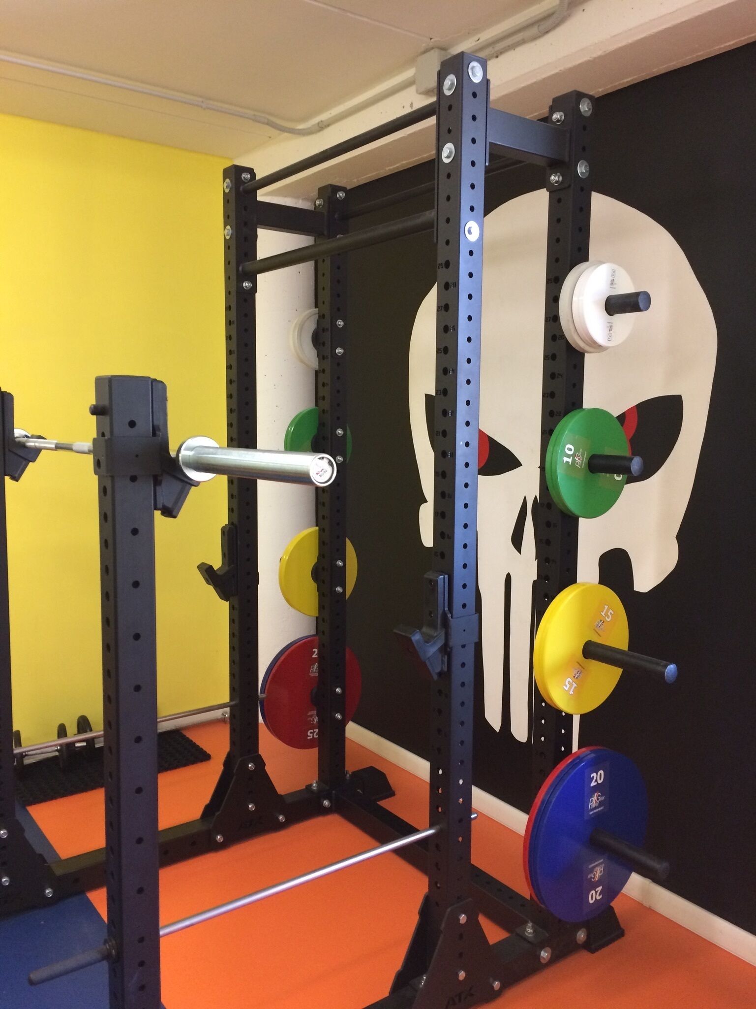 Zona de levantamiento de pesas con jaula para sentadillas, barra y discos.