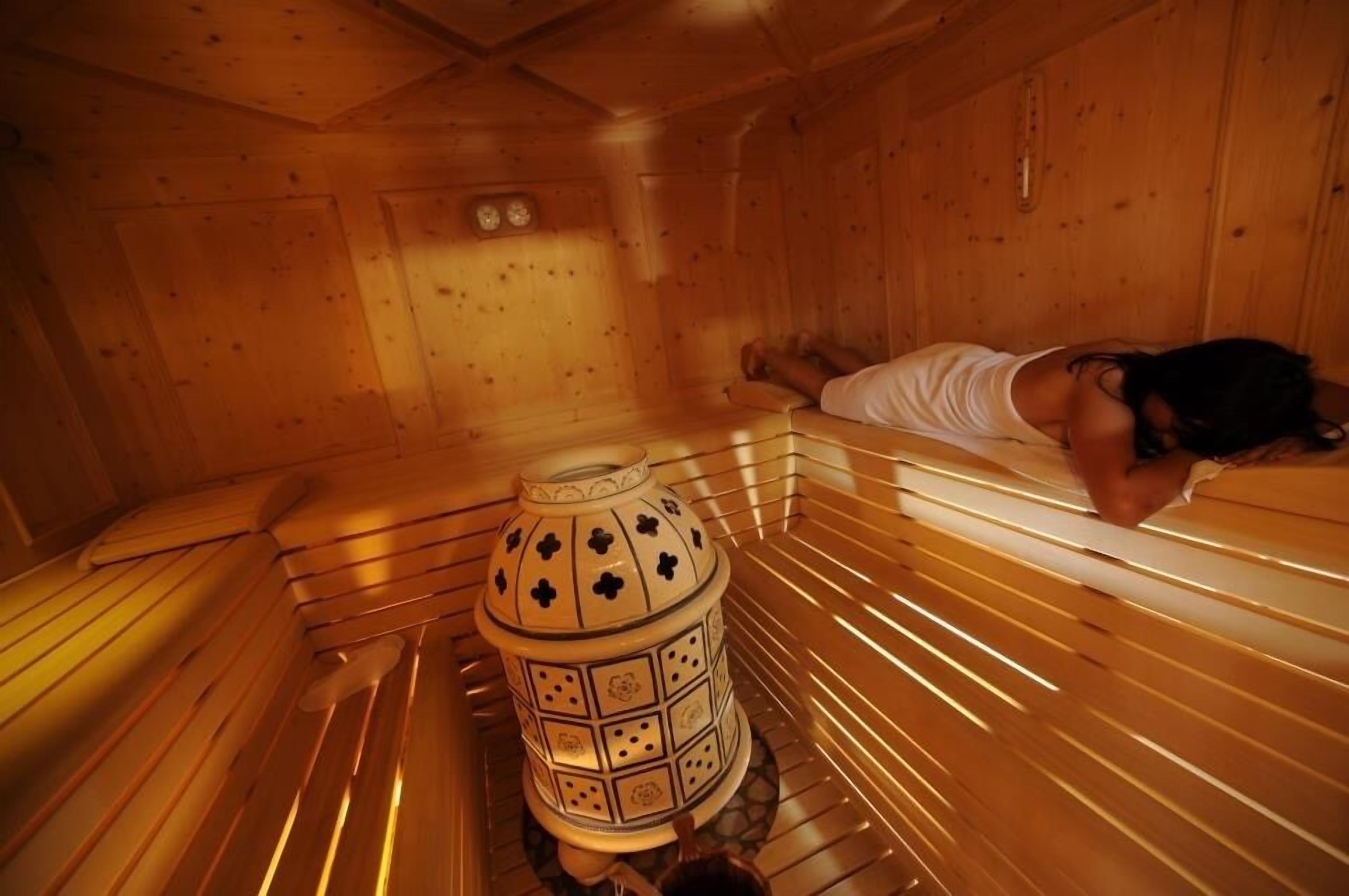 A sauna room with wooden benches and a central decorative urn.