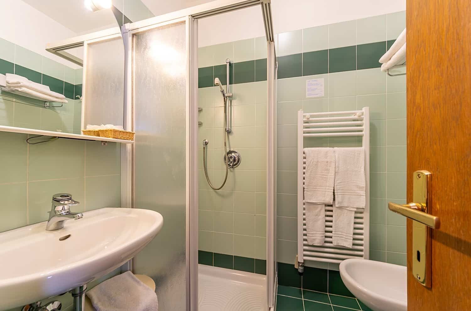 Um banheiro com chuveiro em cabine de vidro, pia e vaso sanitário.