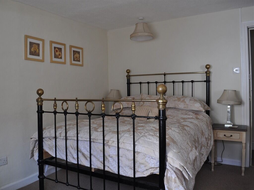 Ein Schlafzimmer mit einem Bett, Nachttischlampen und drei gerahmten Bildern an der Wand.