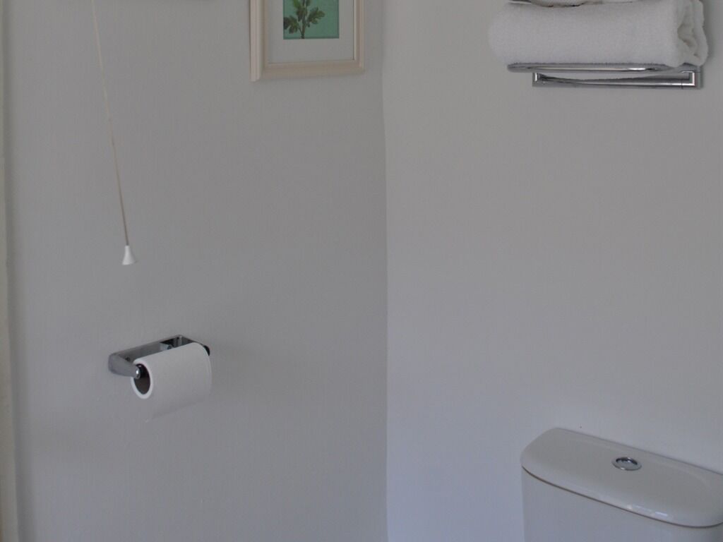 A bathroom with a toilet, a towel rack, and a toilet paper holder.