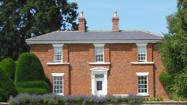A two-story brick house with a symmetrical facade, a central entrance with a white door, and a small porch. - The Grange (Market Rasen)