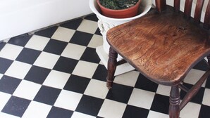A chair with a wooden backrest and seat, positioned on a black and white checkered floor. - The Grange (Market Rasen)