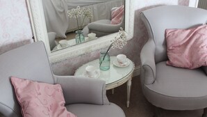 A room with two grey armchairs, a small round table with a cup and saucer, and a mirror reflecting the room. - The Grange (Market Rasen)