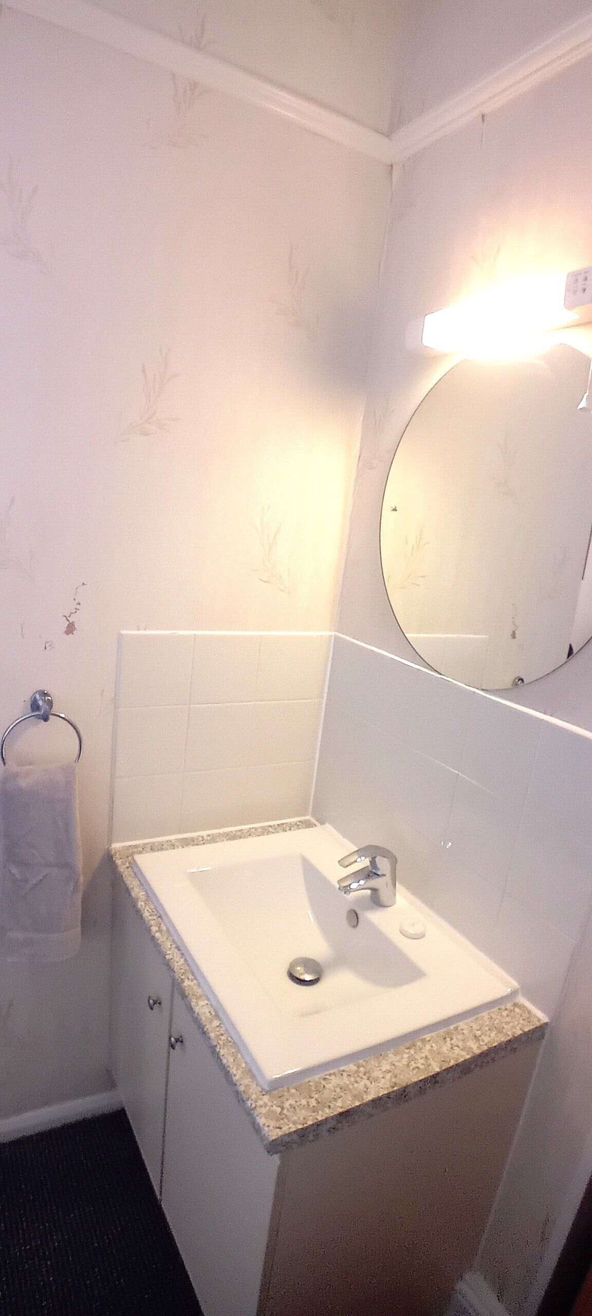 A bathroom with a white sink, a mirror, and a towel rack.