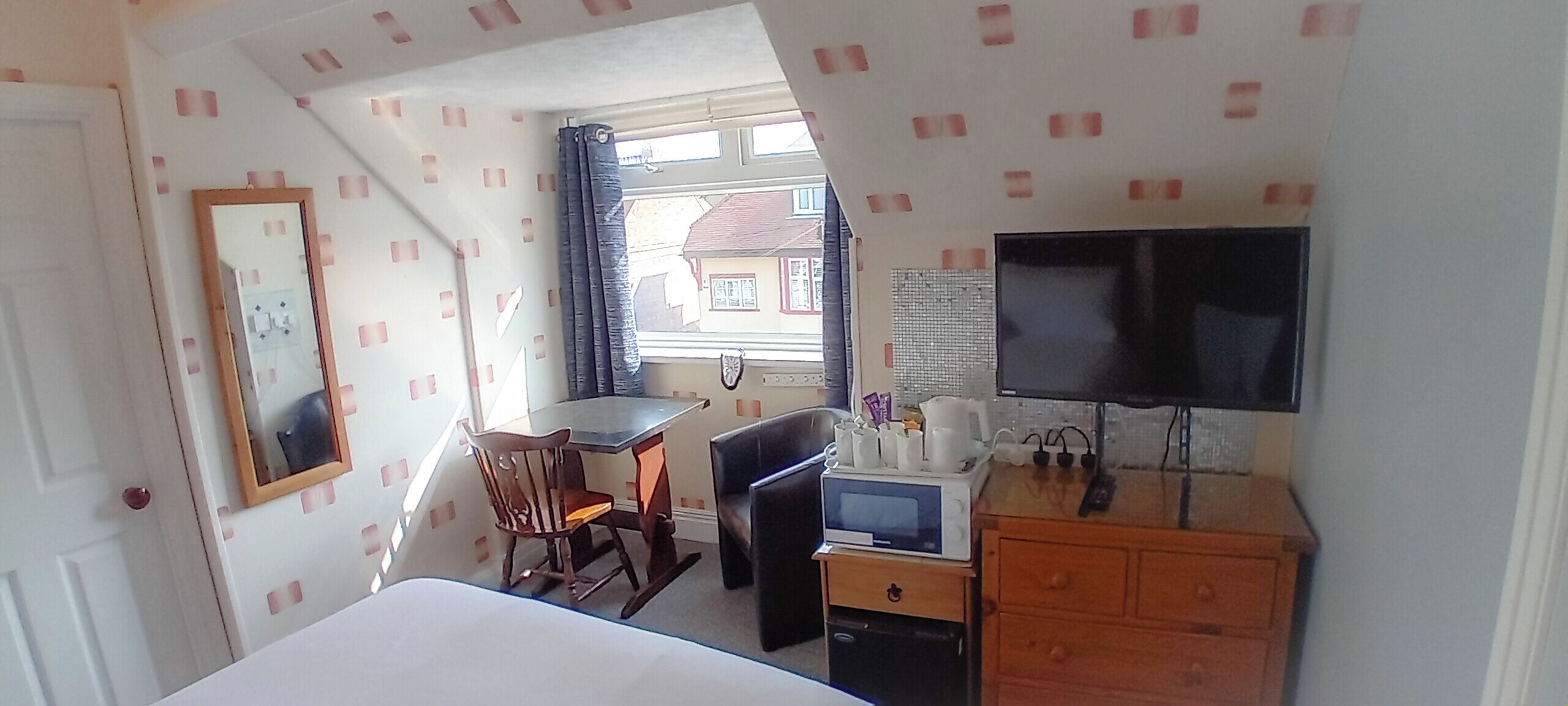 Une chambre d’hôtel comprenant un lit, un bureau avec une chaise, une télévision, un four à micro-ondes et une commode.