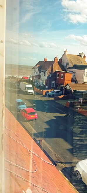 A coastal street with parked cars and buildings. - Home and Away Guesthouse (Bridlington)