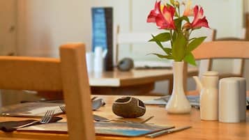 A dining table with a vase of flowers, salt and pepper shakers, and a decorative stone.