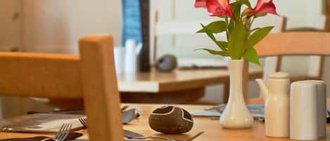 A dining table with a vase of flowers, salt and pepper shakers, and a decorative stone.
