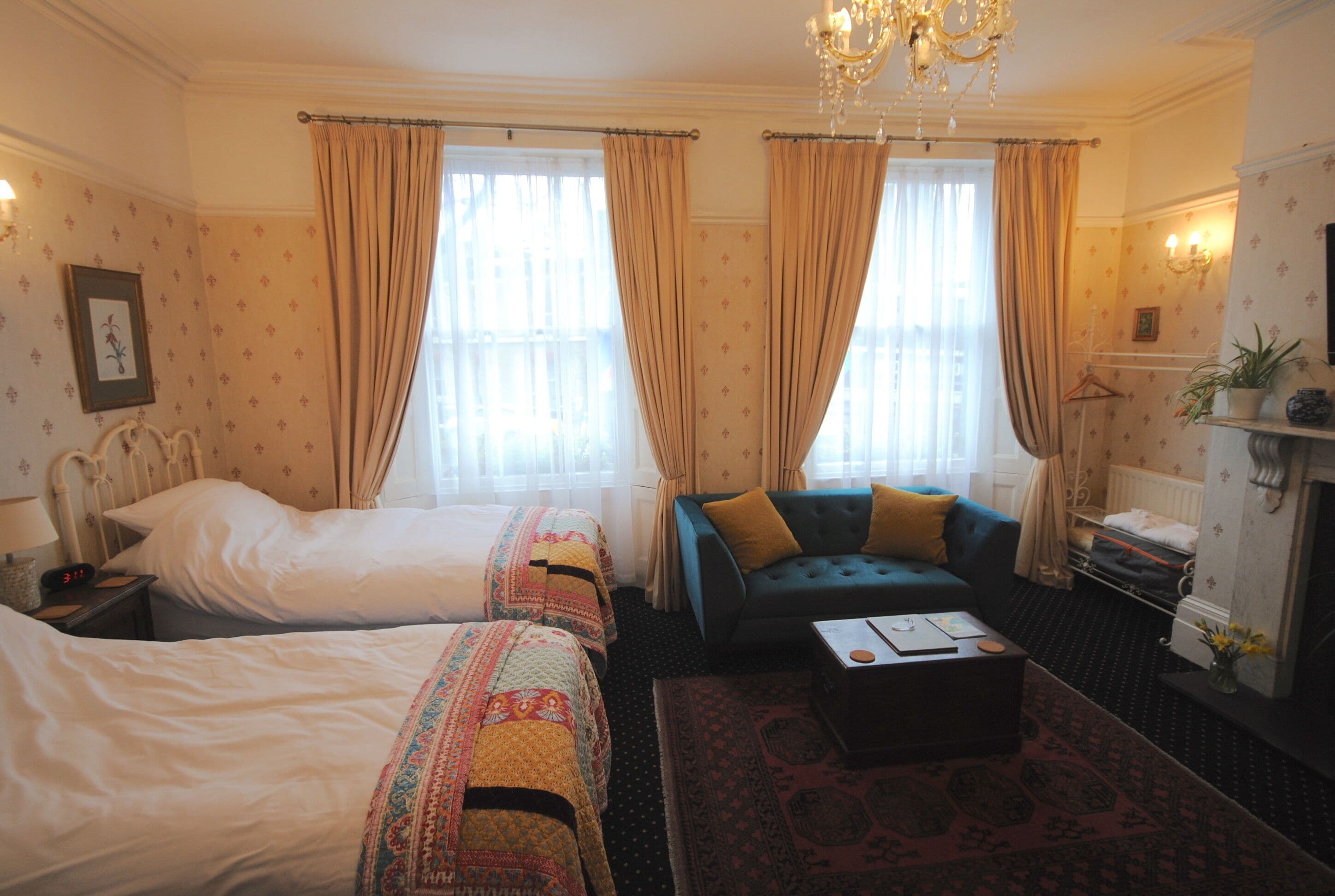 A hotel room with two beds, a sofa, a coffee table, and a chandelier.