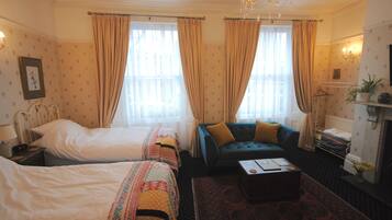 A hotel room with two beds, a sofa, a coffee table, and a chandelier.