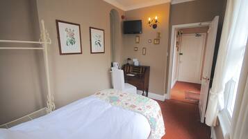 A hotel room with a bed, a desk, a chair, a television, and a door leading to another room.