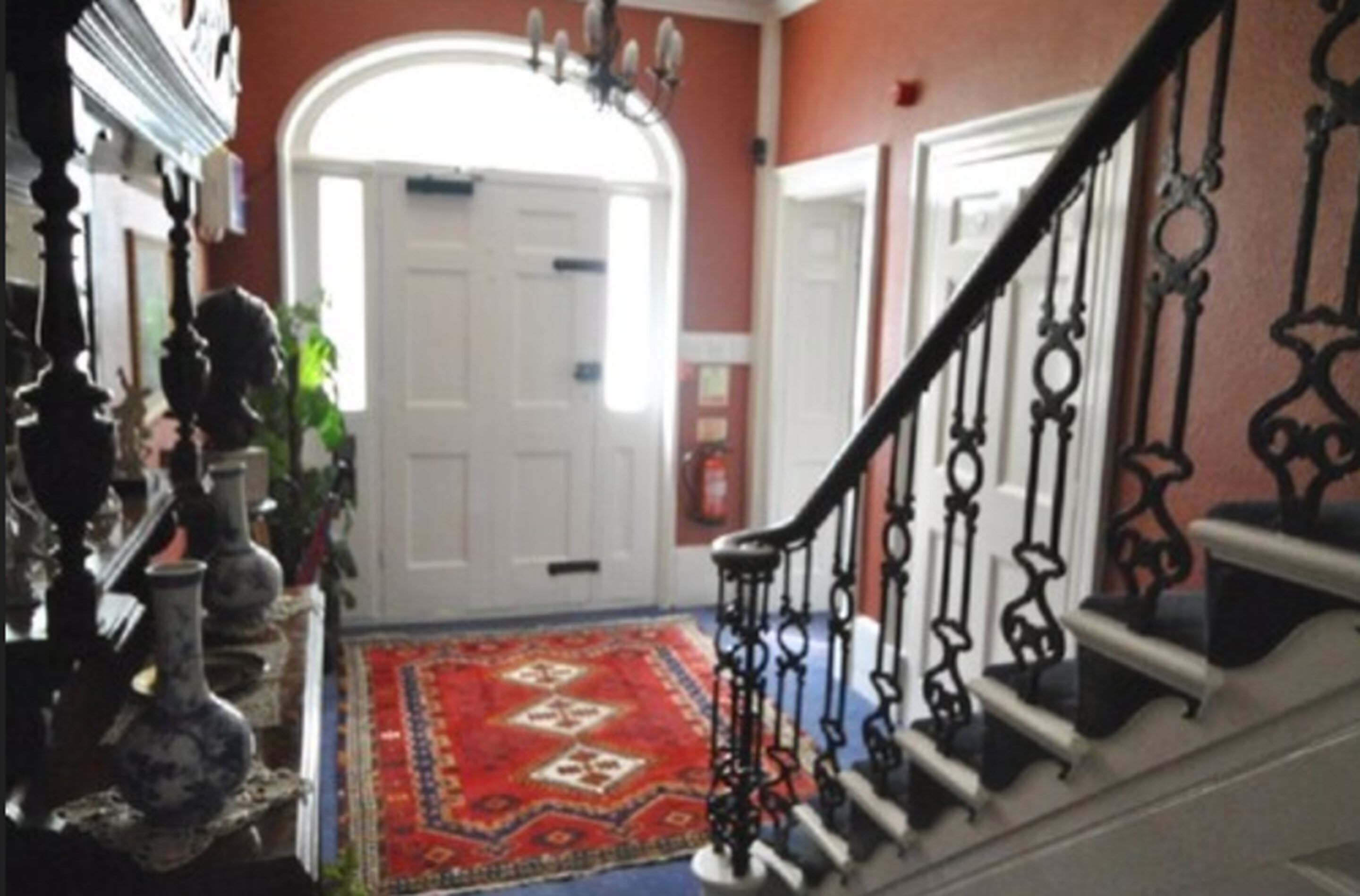 A staircase with ornate black railings leading to a white door.