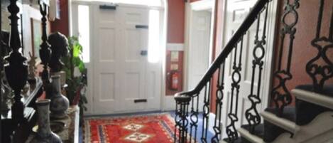A staircase with ornate black railings leading to a white door.