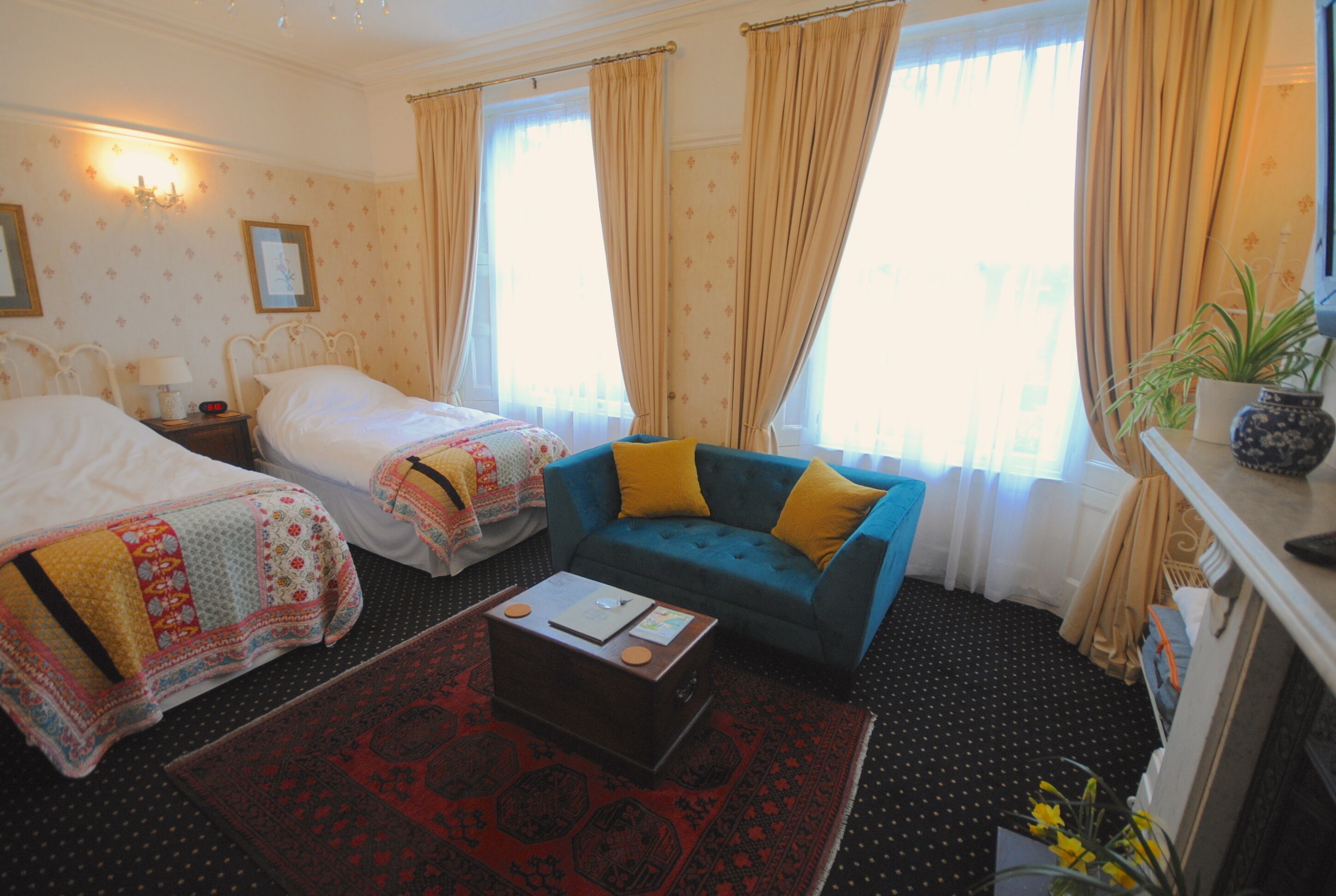 A hotel room with two beds, a sofa, a coffee table, and a window with curtains.