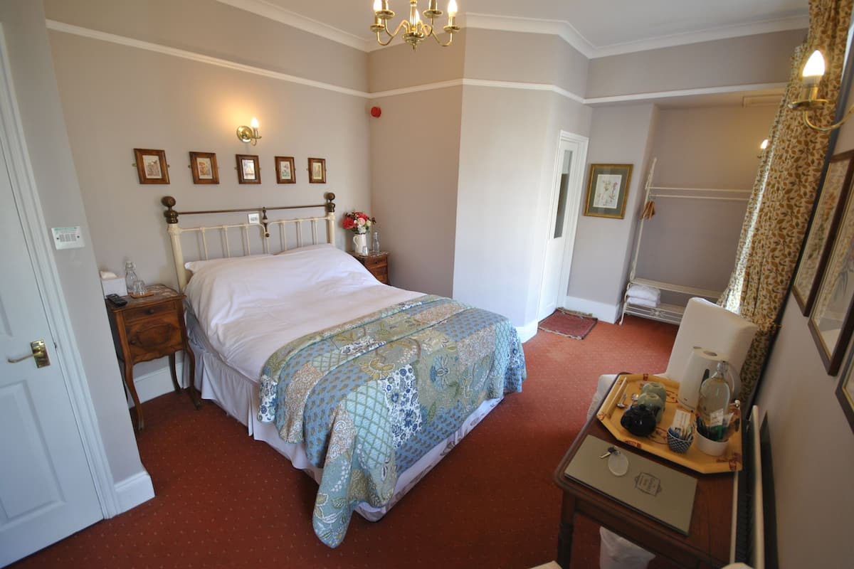 A bedroom with a bed, bedside table, nightstand, and a dresser with a mirror.