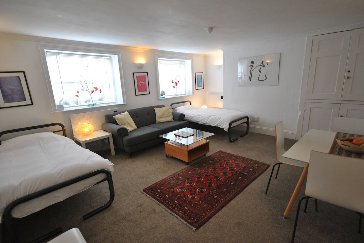 A modern, well-lit bedroom with two single beds, a sofa, a coffee table, and a dining area.