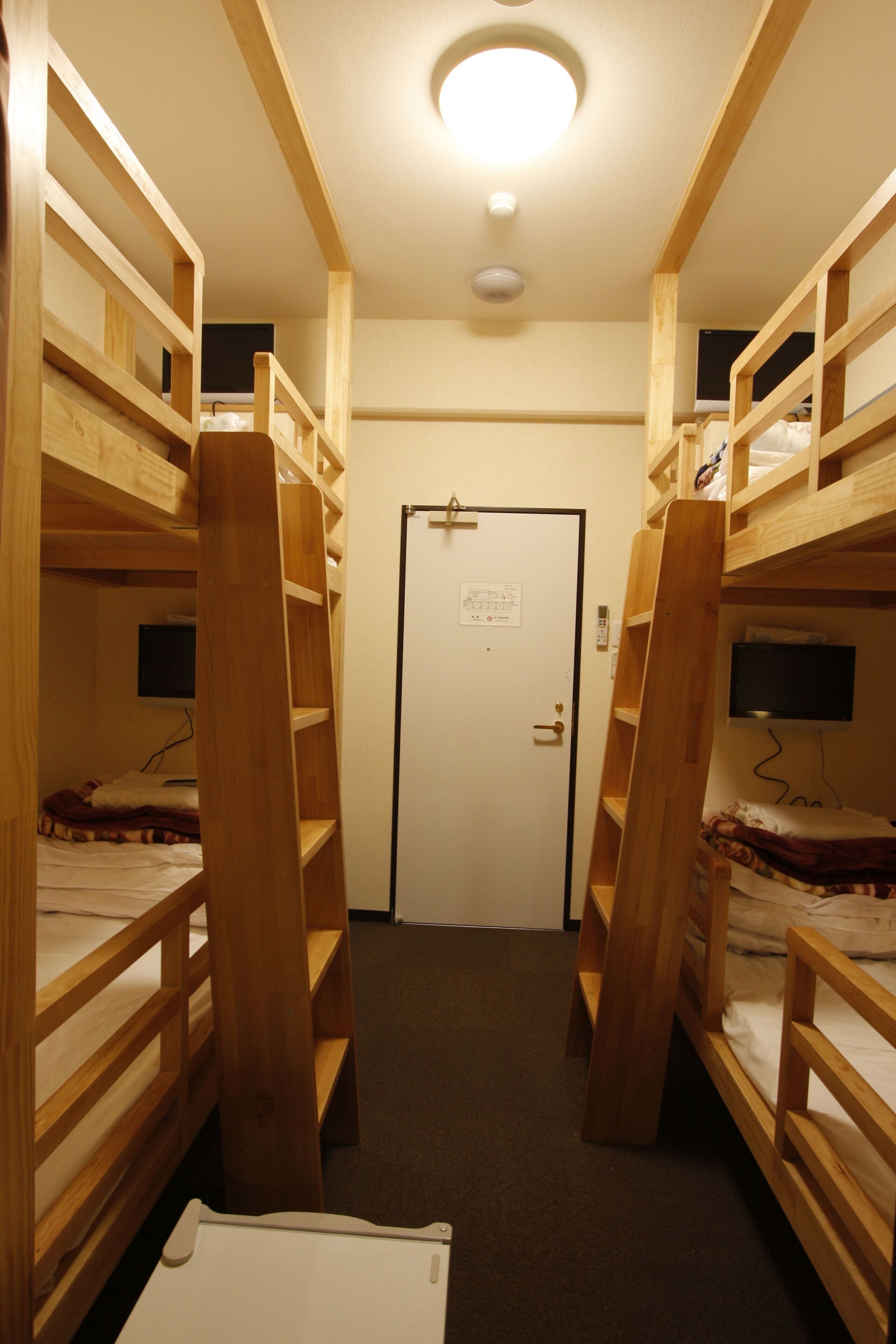 A corridor with bunk beds, a door, and a ceiling light.