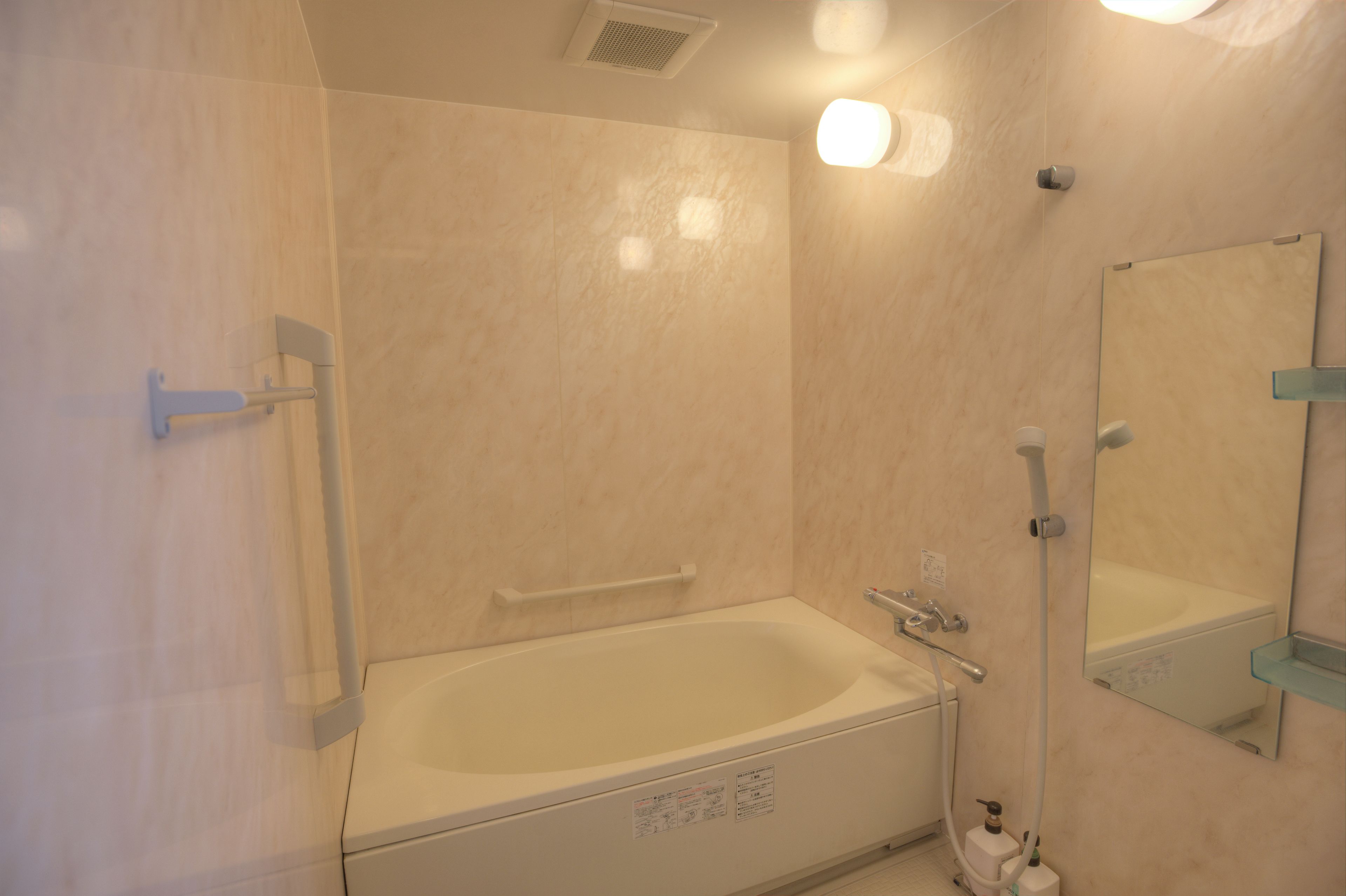 Un baño con bañera, ducha, inodoro, espejo y barandilla.