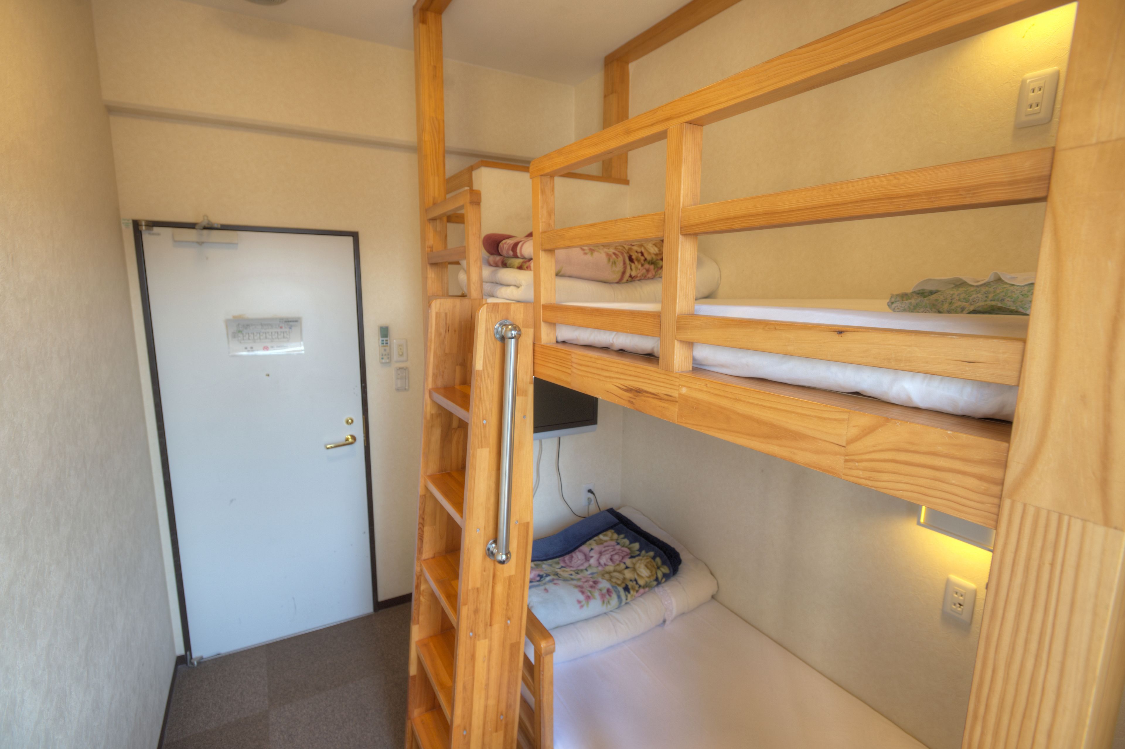 A compact room with bunk beds, a door, and a small shelf.