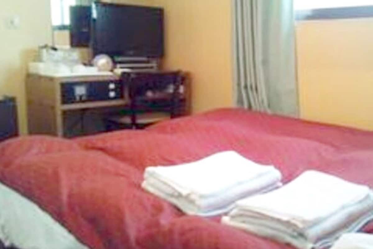 Quarto de hotel com cama, televisão e escrivaninha com cadeira.