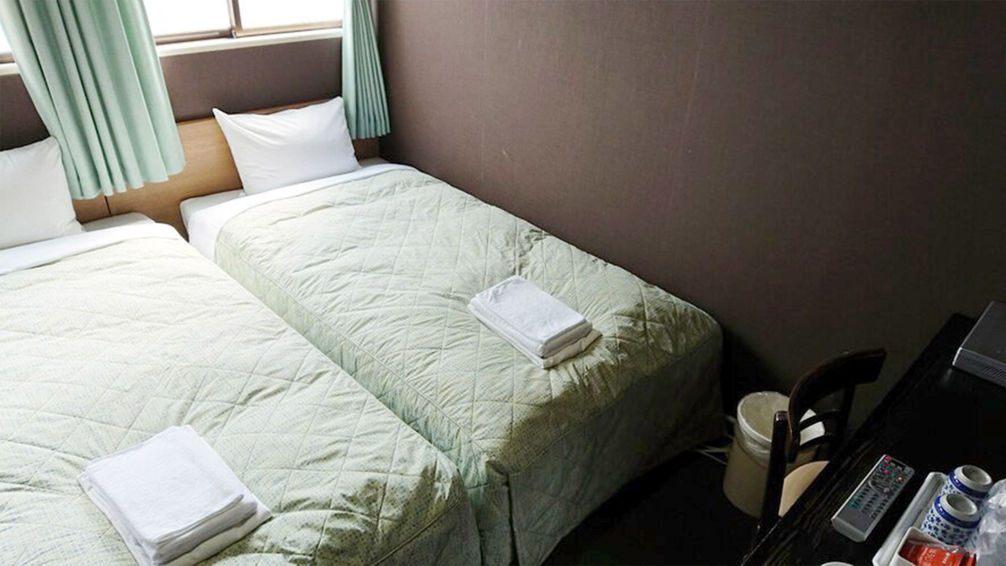 Una habitación de hotel con dos camas, un escritorio con una computadora y una silla.