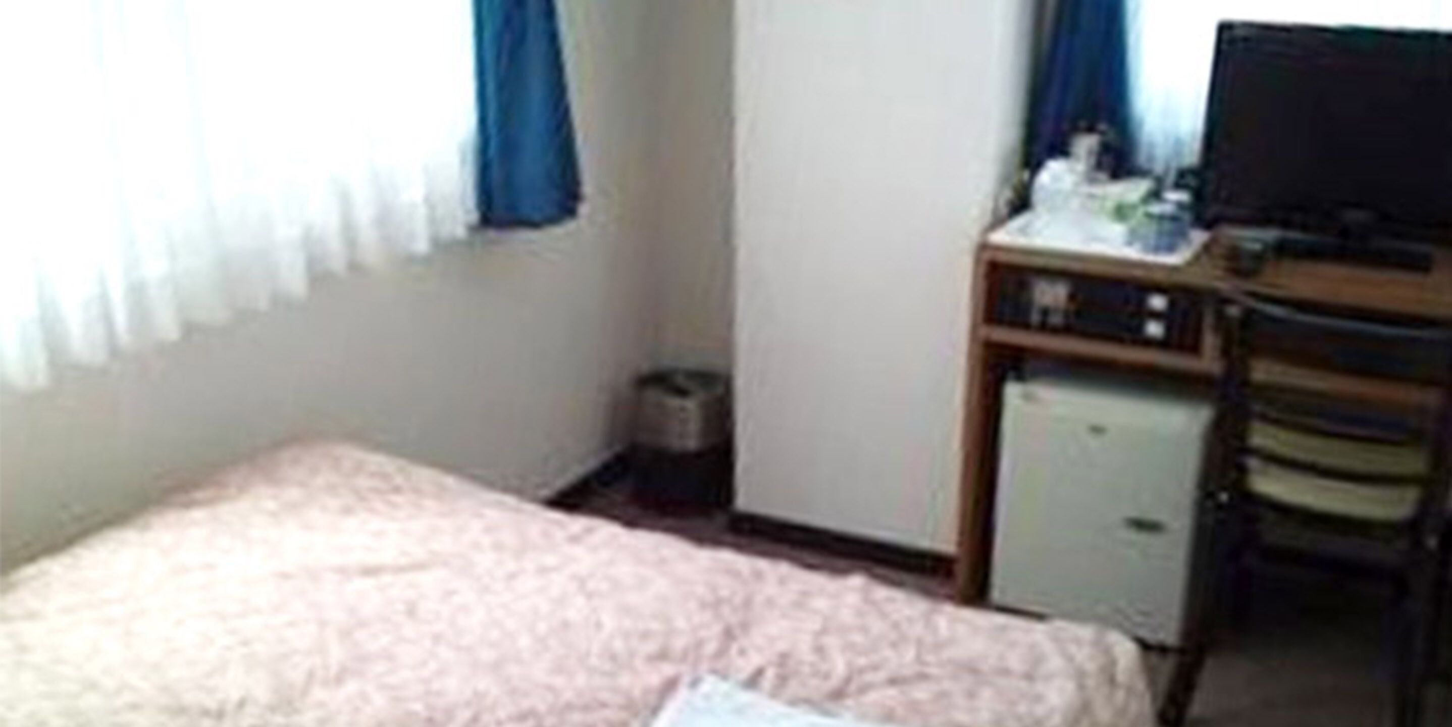 A small room with a bed, a desk, a chair, and a television.
