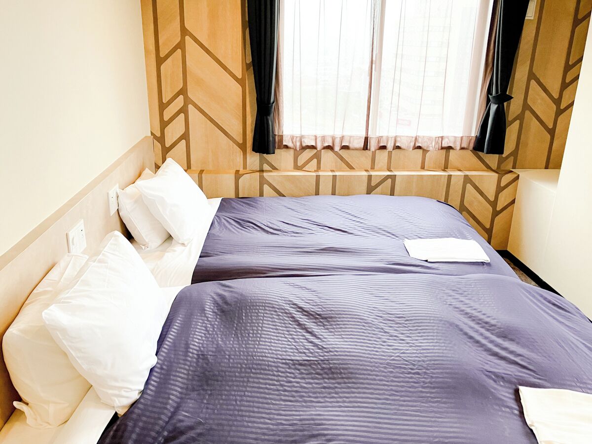 A double bed with a headboard featuring a geometric pattern, white pillows, and a dark blue bedspread.