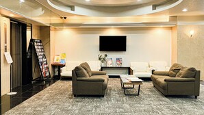 A modern lobby with a seating area, a flat-screen TV mounted on the wall, and a magazine rack. - HOTEL LiVEMAX Kobe (Kobe)