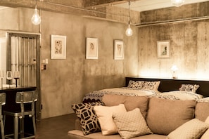Um quarto com uma cama, um espaço de bar com banquetas e obras de arte nas paredes.