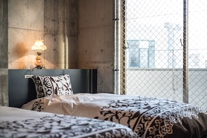Quarto com cama, mesa de cabeceira, luminária e vista através de uma cerca de arame.