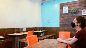 A restaurant interior with wooden tables and orange chairs, a blue wall, and a wooden accent wall with a sign. - Guesthouse CamCam Okinawa - Hostel (Naha)