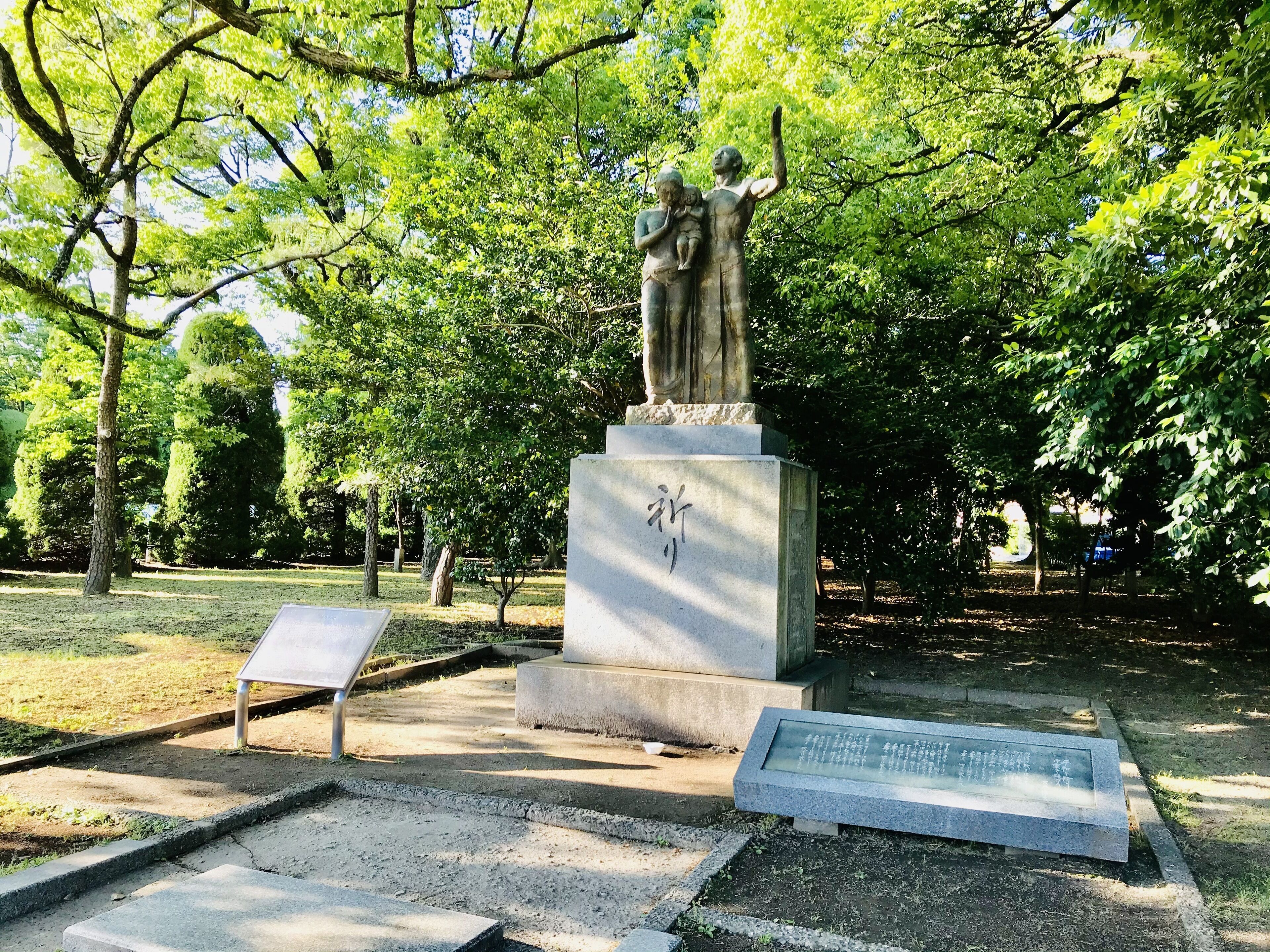 A statue in a park with a stone base and a plaque.