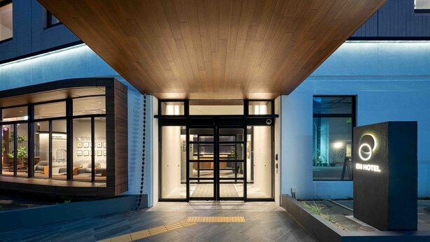 A hotel entrance with a modern design, featuring a wooden overhang and glass doors. - EN HOTEL Hiroshima (Hiroshima)