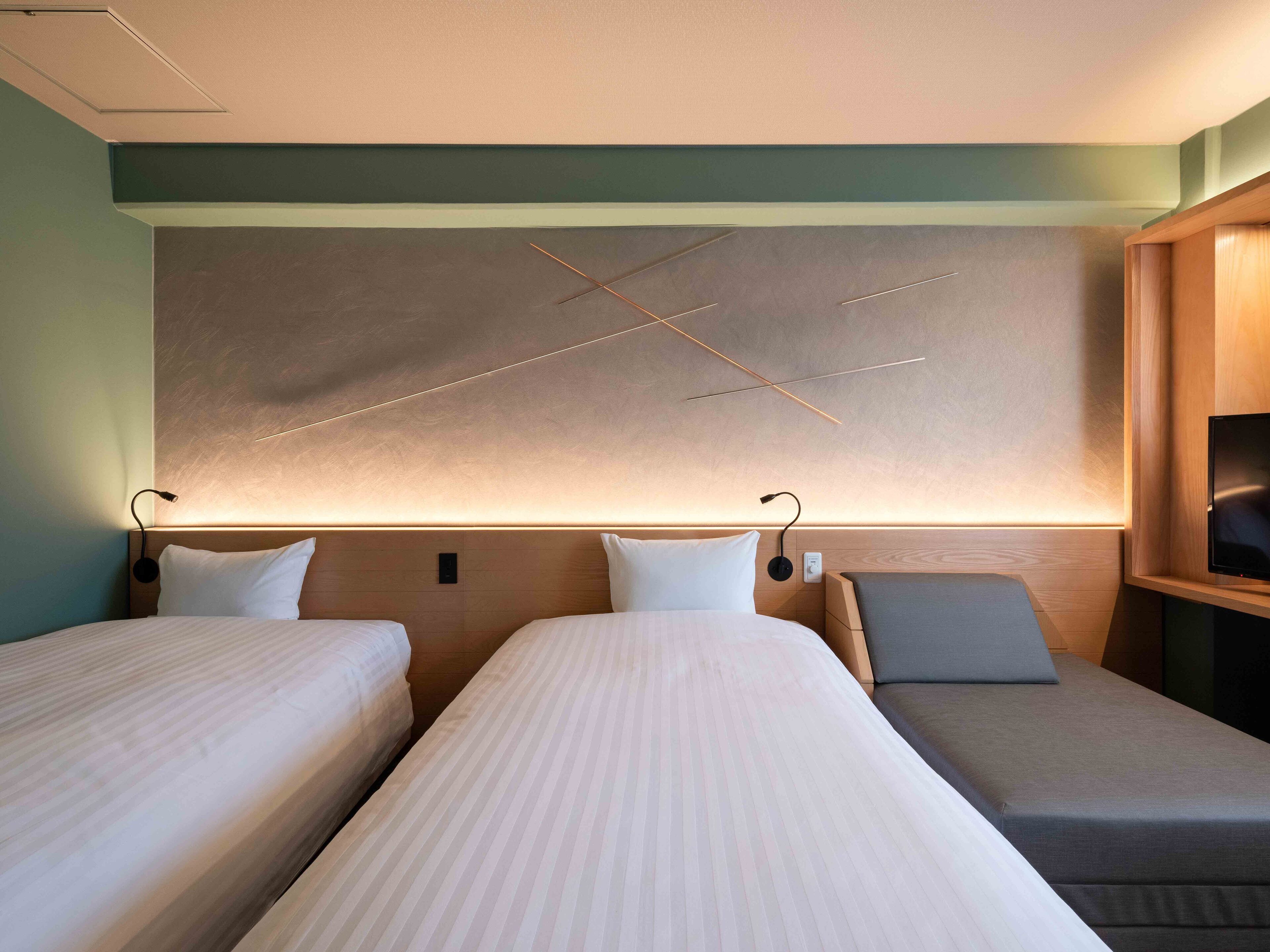 Quarto de hotel com duas camas, uma obra de arte grande na parede e um armário de madeira com televisão.