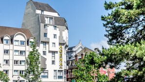 Un hotel de varios pisos con un llamativo letrero 'AGENDA', que presenta un diseño moderno con una mezcla de estilos arquitectónicos.