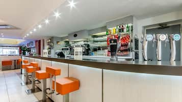 A modern bar area with orange stools, a counter with beer taps, and a visible coffee machine.