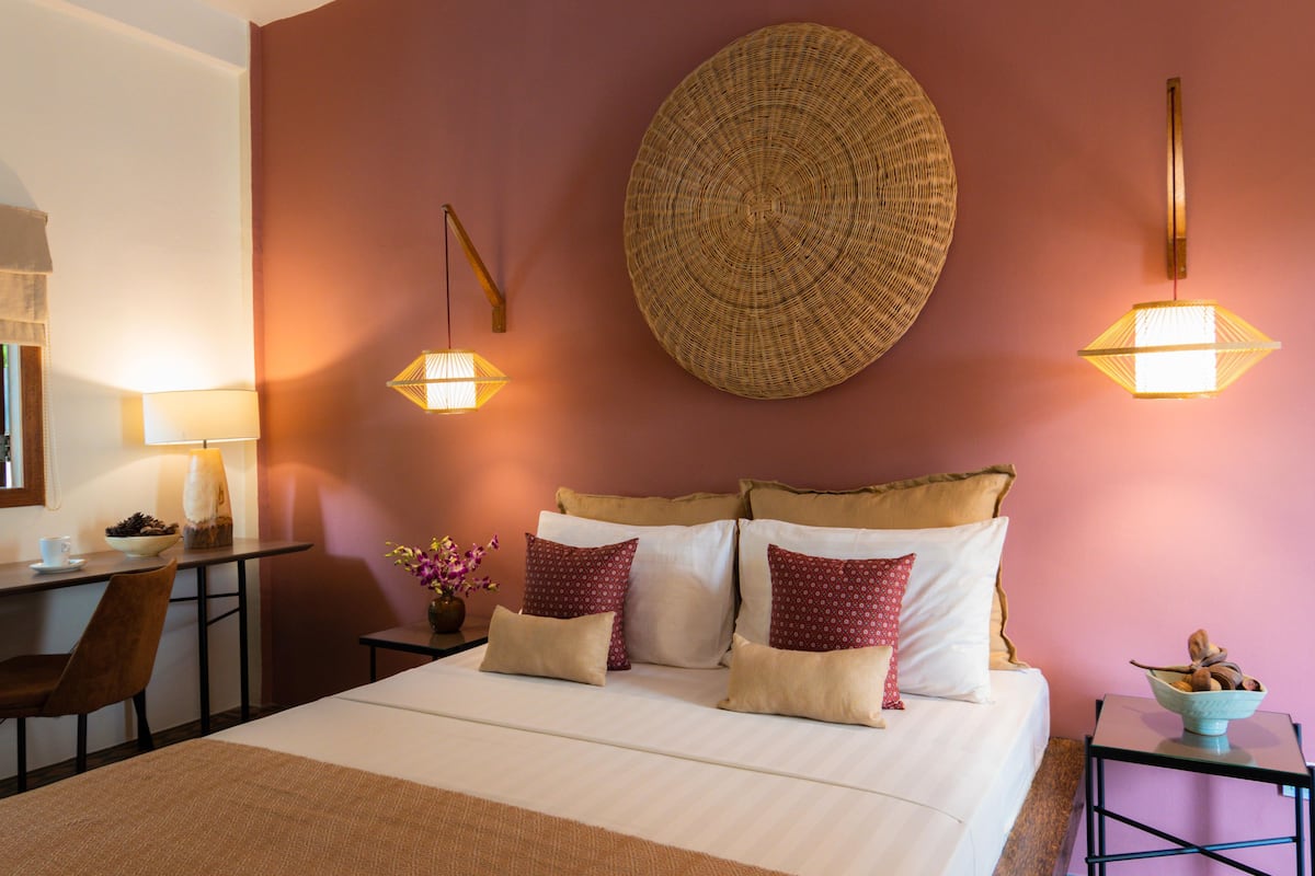 A hotel room with a bed, bedside tables, a desk, and a chair.