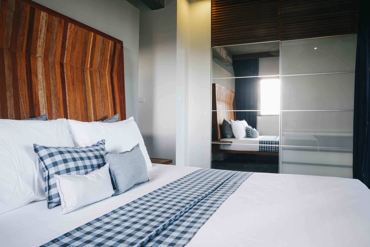 A modern bedroom with a large bed, checkered bedding, and a wooden headboard.