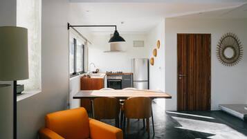 Une cuisine moderne avec un coin repas, comprenant une grande table, des chaises et un luminaire suspendu.