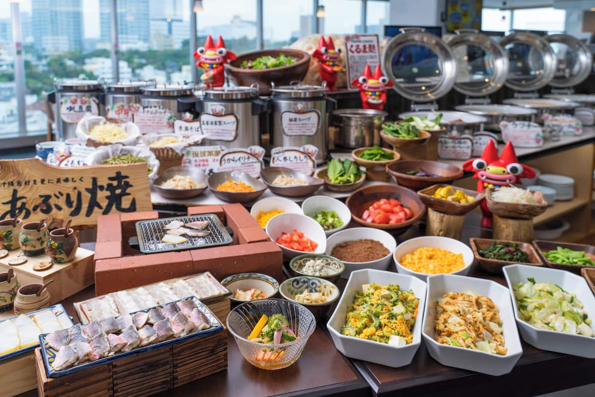 A variety of food items and containers on a table, including bowls of vegetables, a tray of fish, and several small jars with labels.