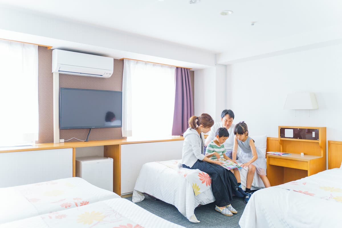 A hotel room with a bed, a desk, a television, and a window with curtains.