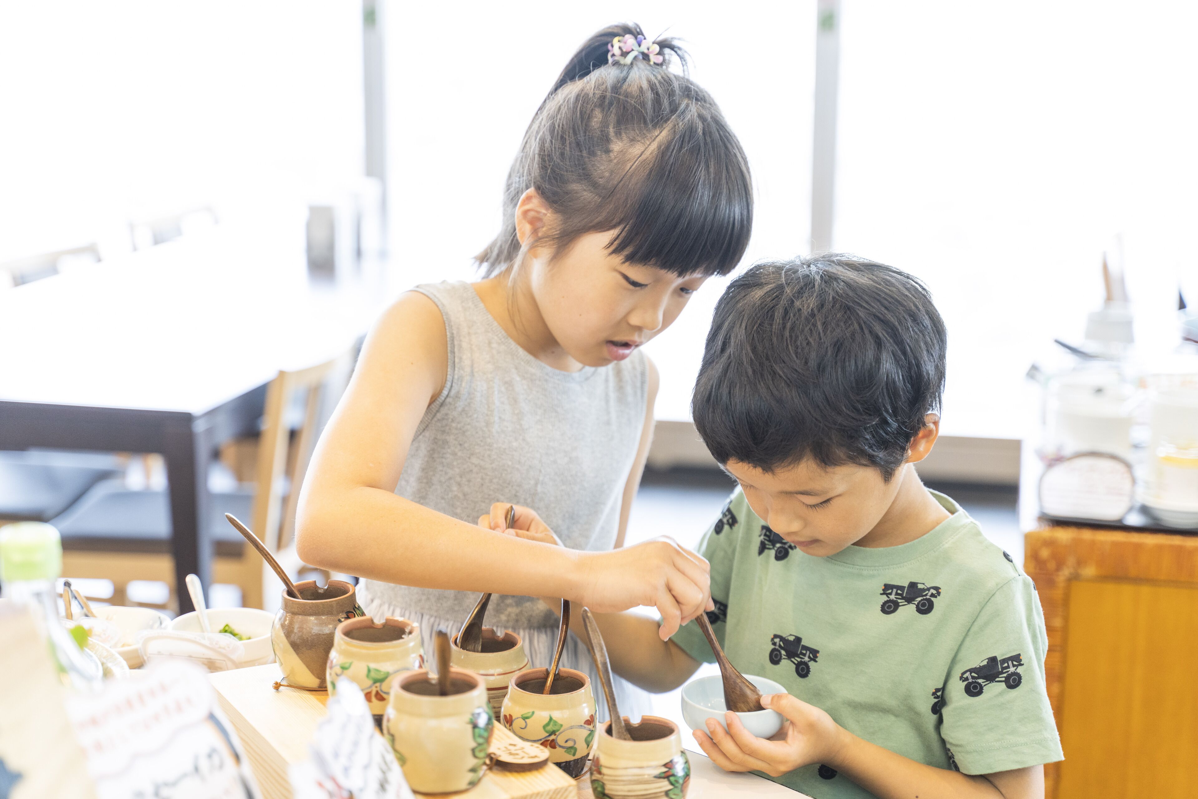 Two children at a table with pottery and bowls.