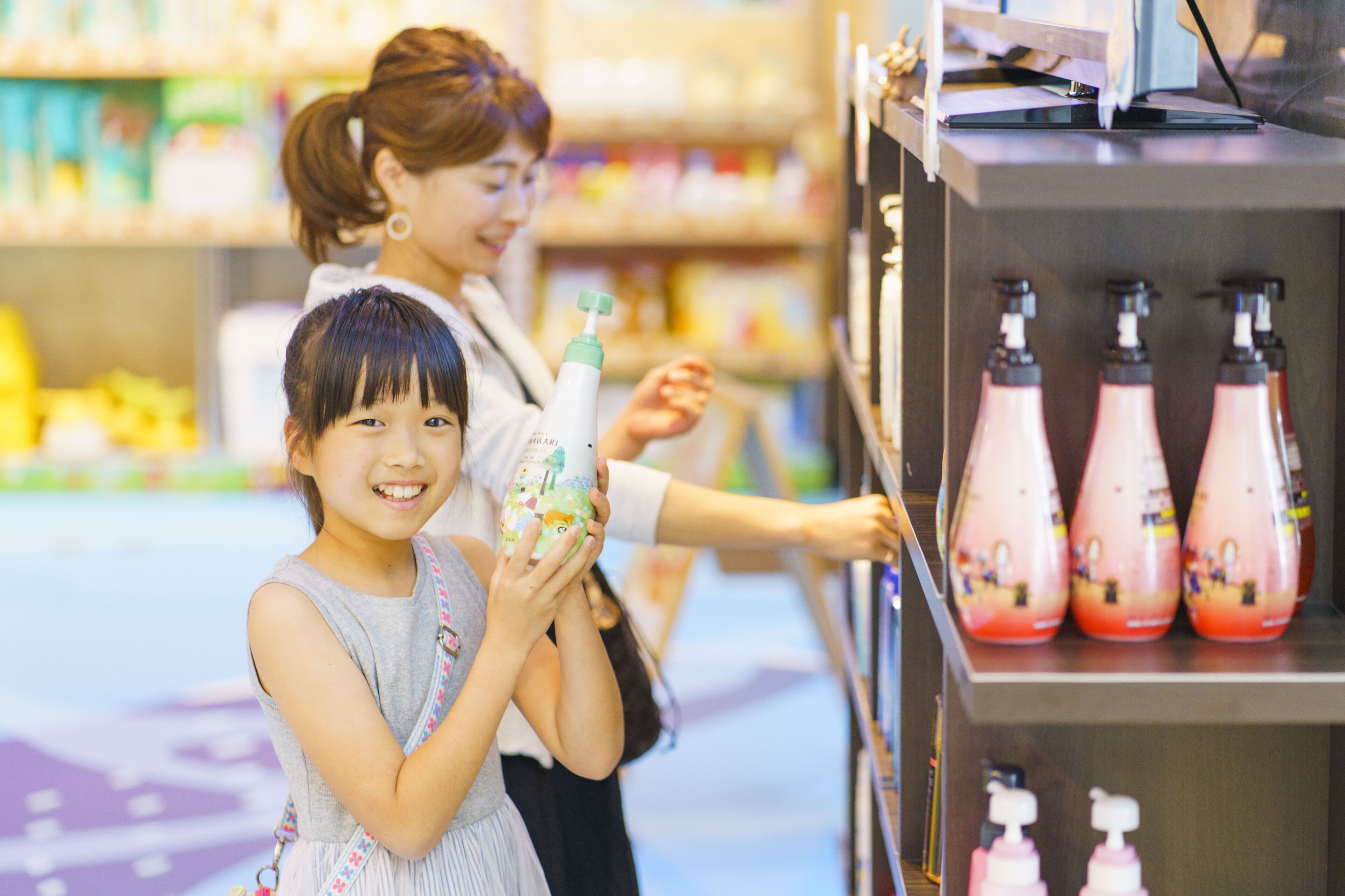 A woman and a child in a store aisle, with shelves stocked with various products.