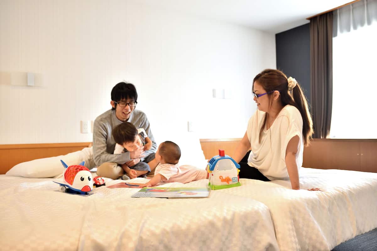A family on a bed with toys and a book.