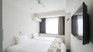 A hotel room with two beds, a large window with curtains, an air conditioning unit, and a mounted television.