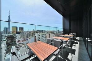 Eine Dachterrasse mit Tischen und Stühlen und Blick auf die Stadt.