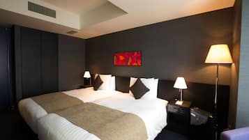 A hotel room with a large bed, two bedside tables, a wall-mounted TV, and a ceiling vent.